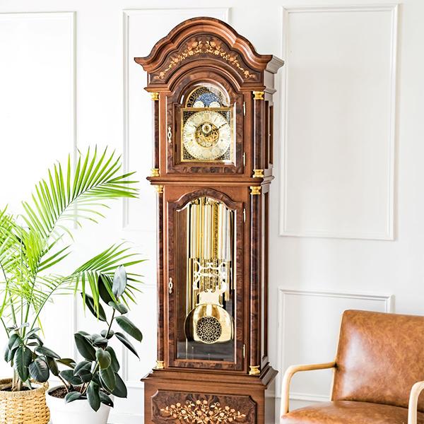 Elaborate grandfather clock stands tall behind rustic farmhouse dining table with candles