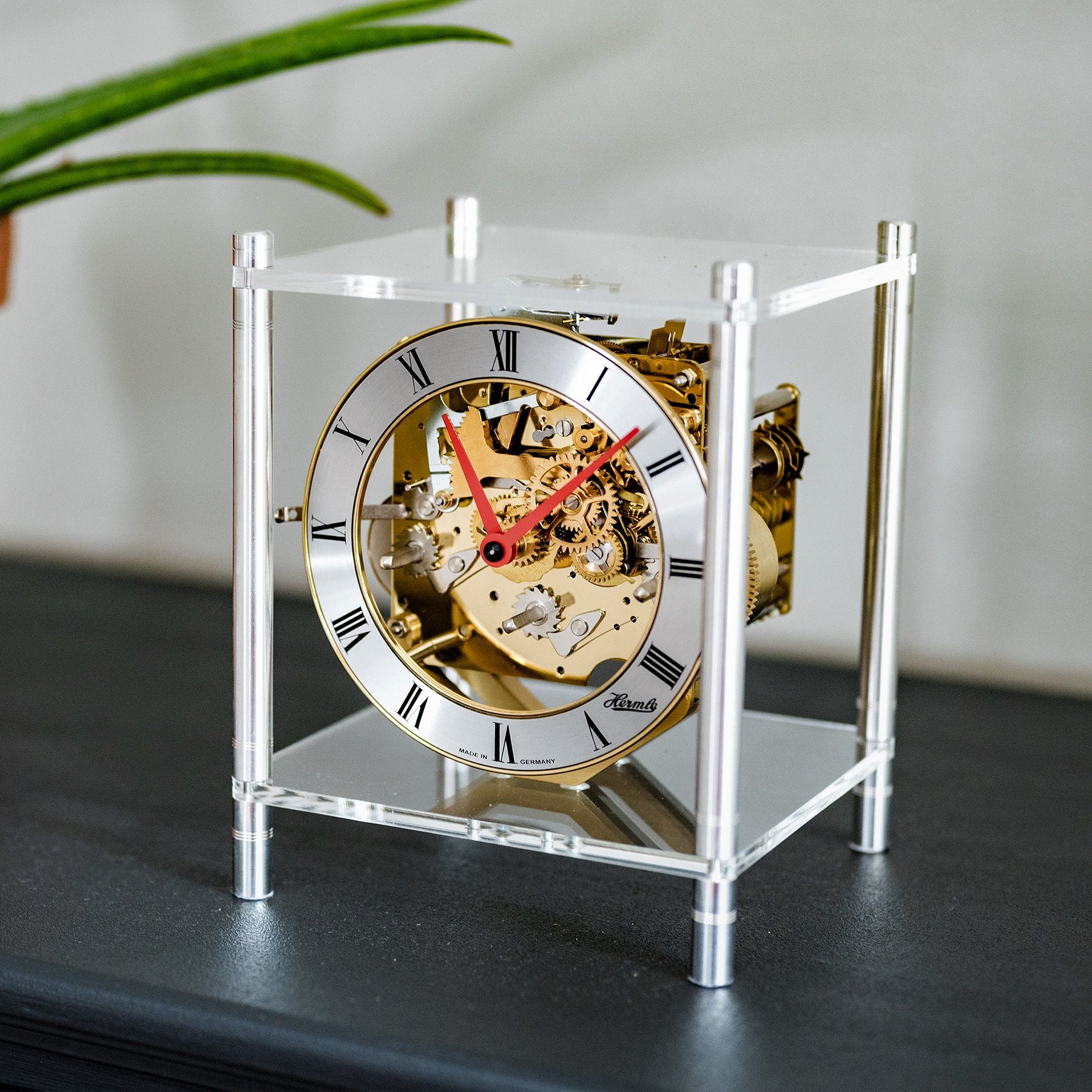 Mid-century walnut tambour mantel clock sits on a shelf in front of artwork