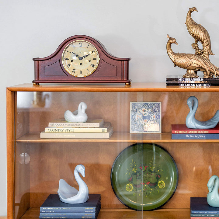 Wood shelf with decor, including a tambour style mantel clock, books, and bird figurines.