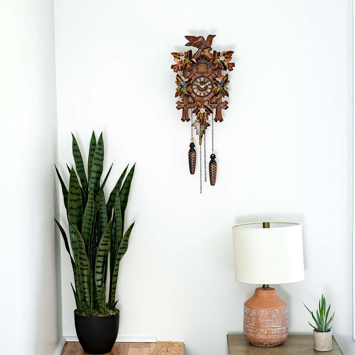 Wooden cuckoo clock in bedroom hanging above potted plant and lamp