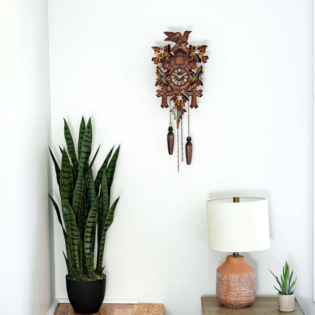 Wooden cuckoo clock in bedroom hanging above potted plant and lamp