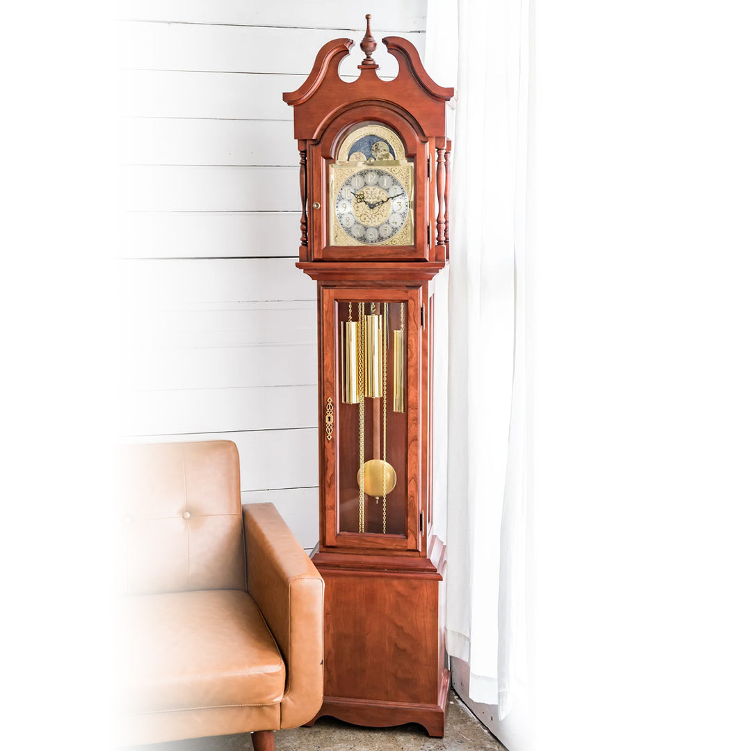 Cherry wood Grandmother clock with brass highlights and silver face in white room