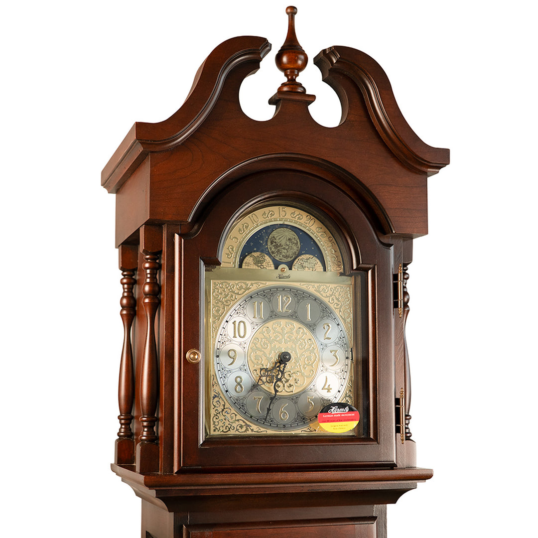 Up close view of cherry wood Grandmother clock with silver face and intricate moon dial 
