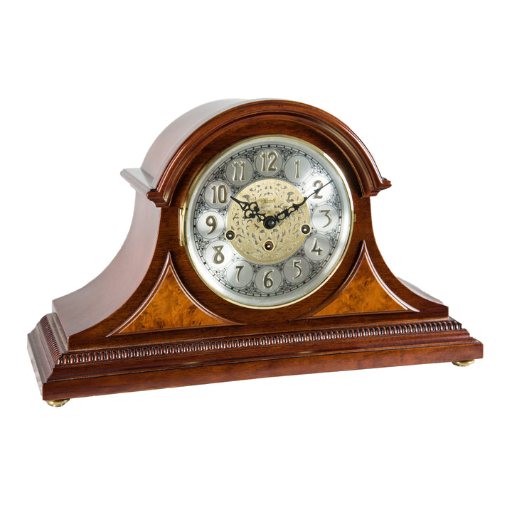 Cherry wood mantle clock with holes for winding the mechanical movement inside on white background