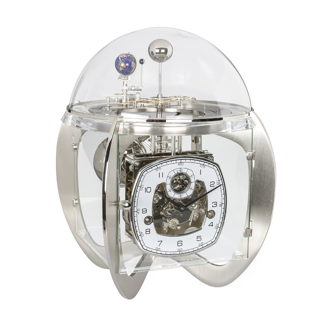 Nickel astronomical clock with visible intricate gears and glass dome on white background.