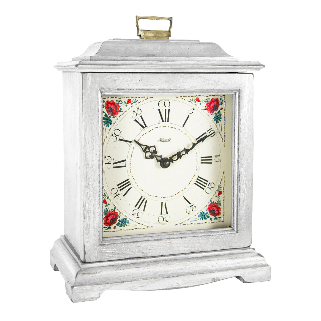 White decorative clock with floral design and roman numerals on a white background