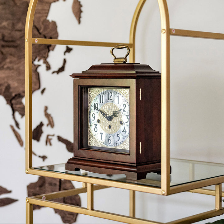 Wooden clock with glass case on a gold and glass shelf against a world map background