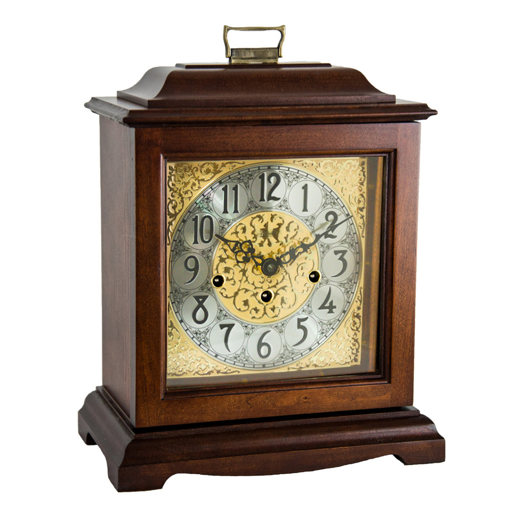 Cherry wood clock with intricate design and holes on the face for winding on a white background