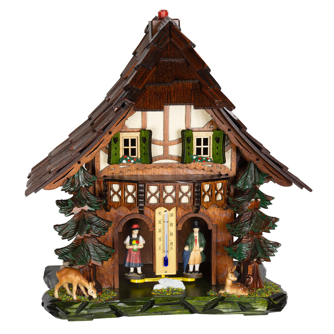Dark wood cuckoo-style weather station with carved green shutters and deer figurines on white background.