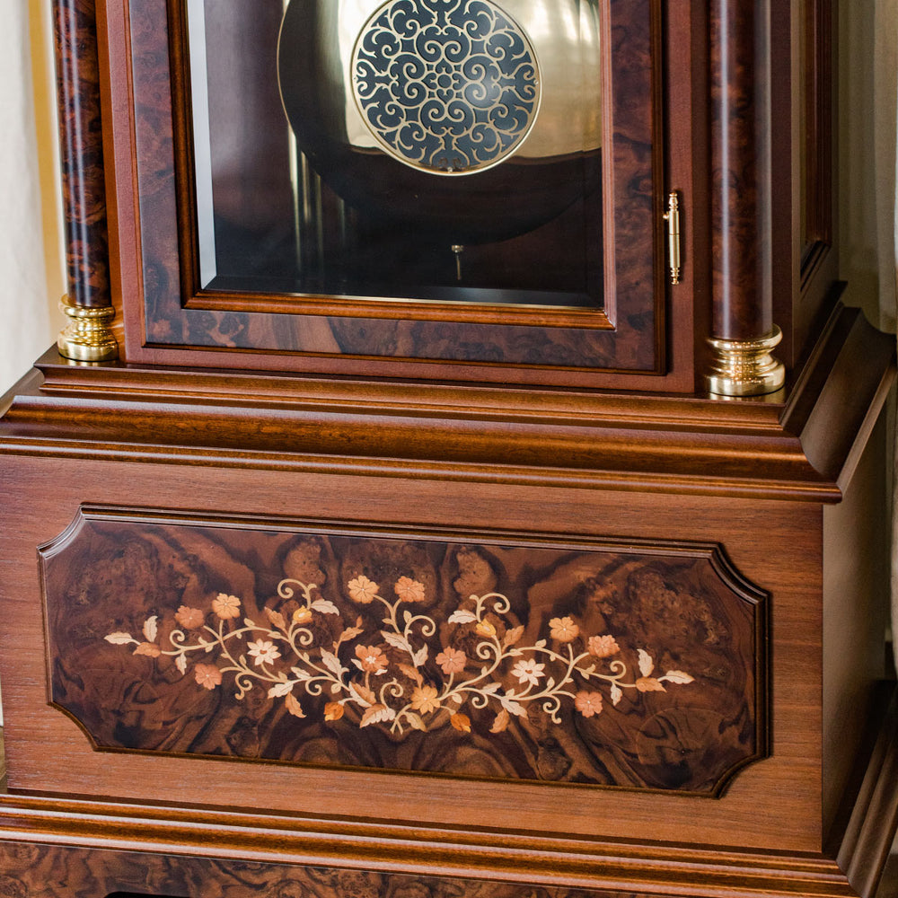 Close up of ornate wooden flower inlay on the base of a grandfather clock