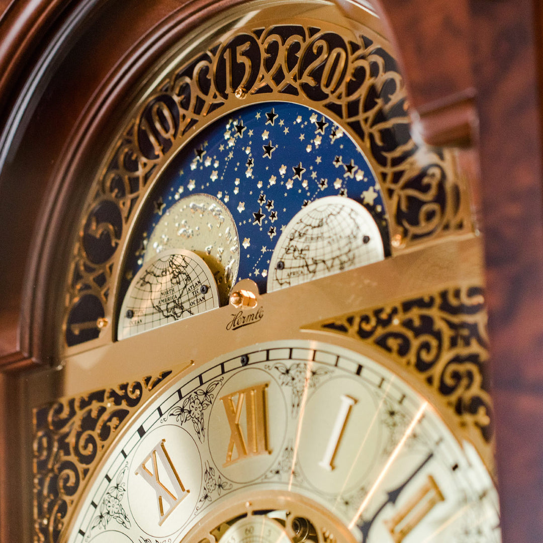 Close-up of an ornate clock face with moon dial and Roman numerals.