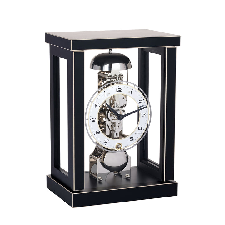 Black wood mantel clock with visible nickel gears and bell on white background
