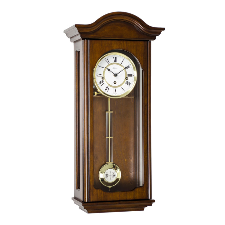 Antique Walnut wood wall clock with brass pendulum and brass highlights around white face on a white background