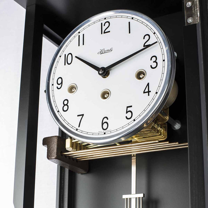Close-up of a clock with a white face and black numbers, featuring the brand 'Hermle'