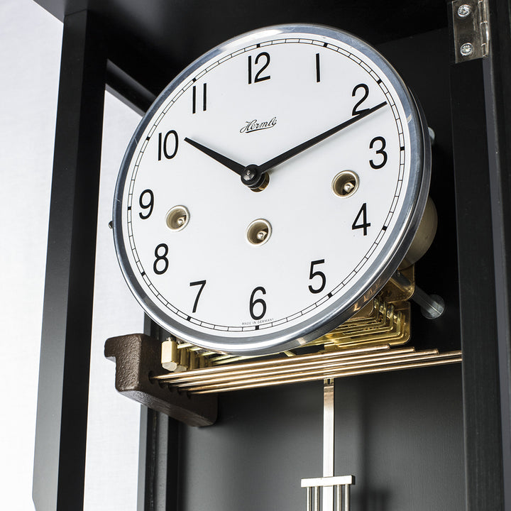 Close-up of a clock with a white face and black numbers, featuring the brand 'Hermle'
