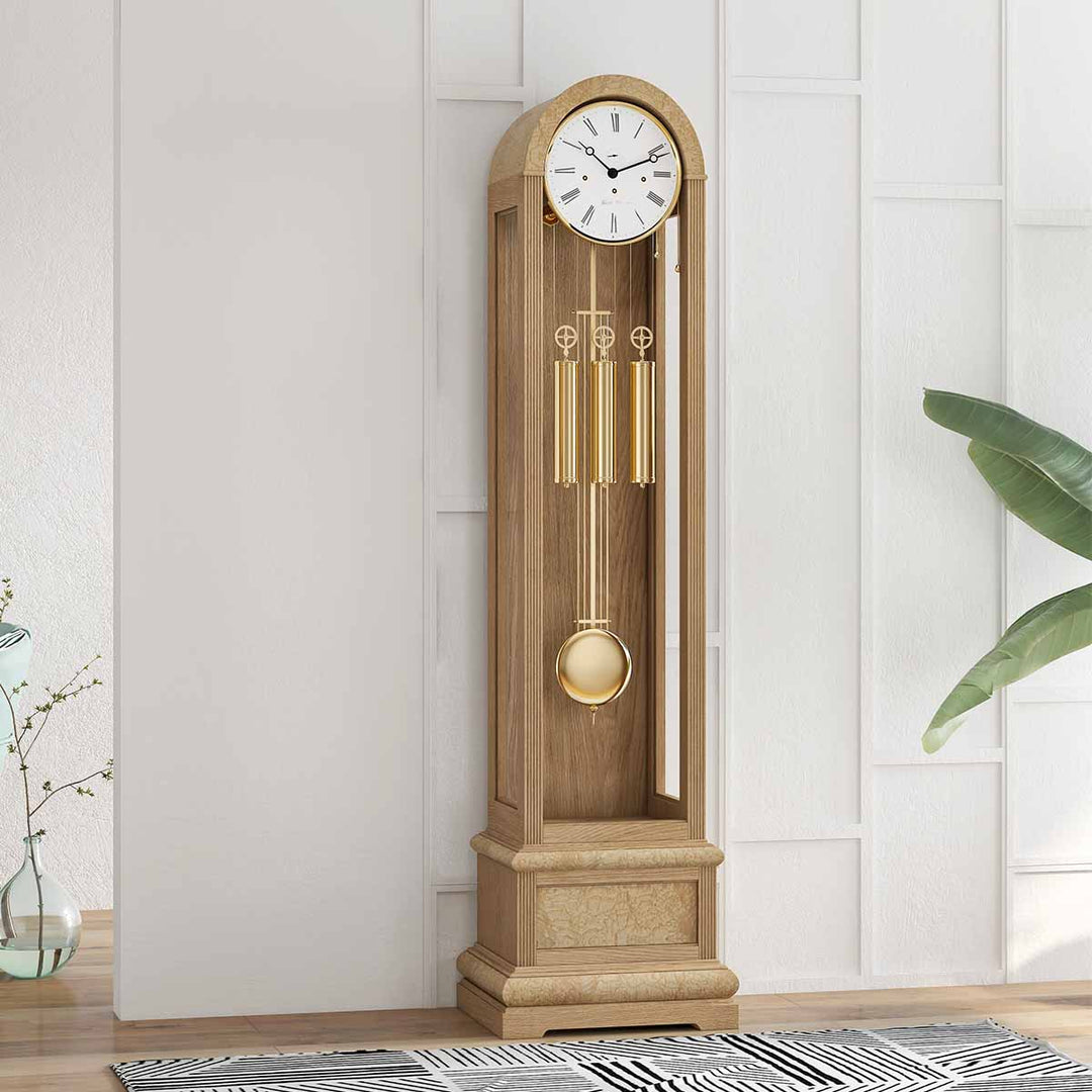 Oak grandfather clock in front of white wall with black and white rug on the floor