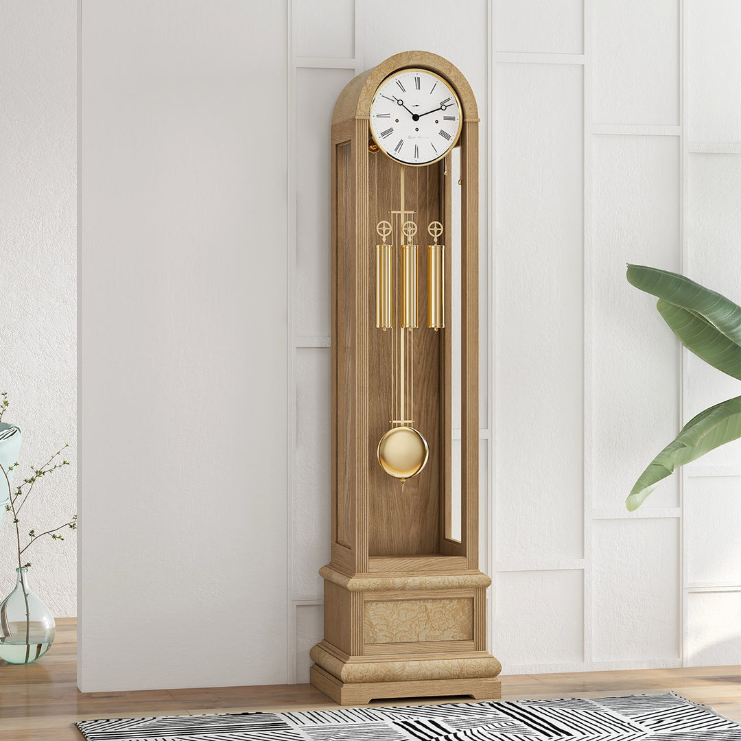 Oak grandfather clock in front of white wall with black and white rug on the 