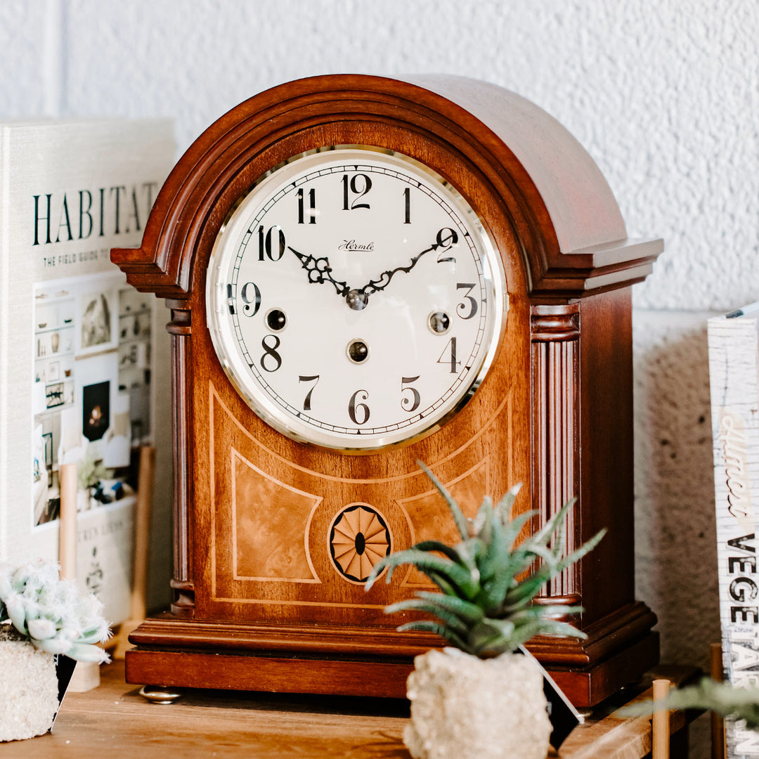 Clearbrook wooden mantel clock on table with books and miniature potted plants in front of white wall