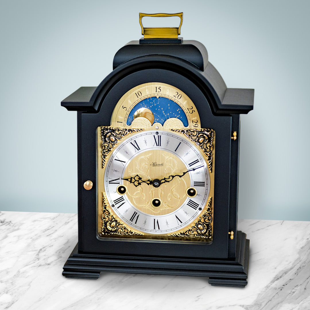 Black and brass clock on marble shelf in front of pale blue wall in living room