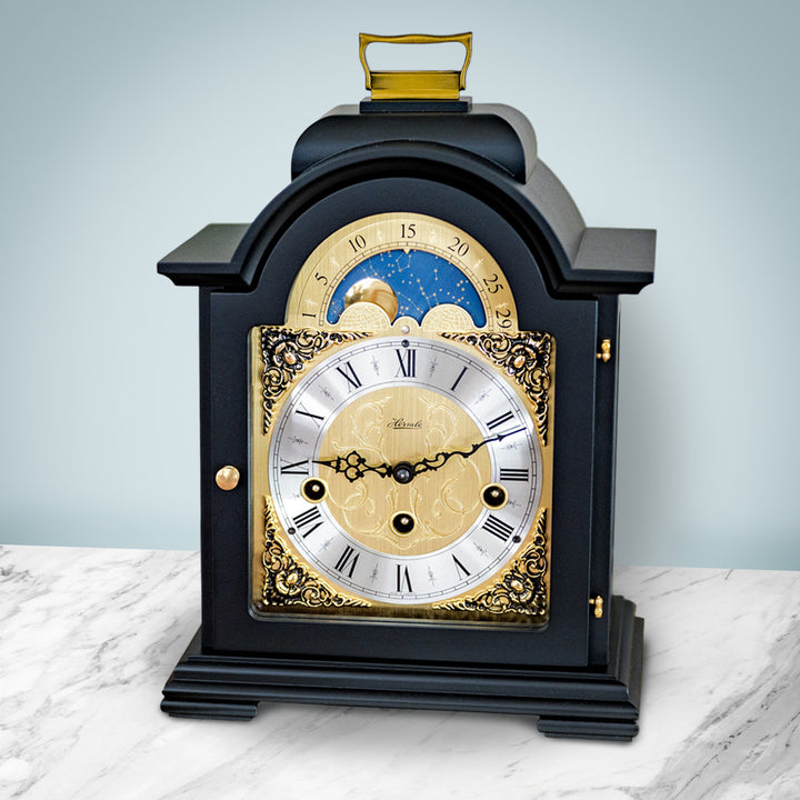 Black and brass clock on marble shelf in front of pale blue wall in living room