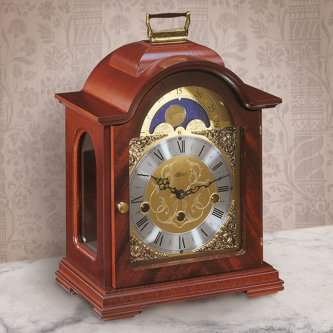 Mahogany and brass clock on white marble shelf