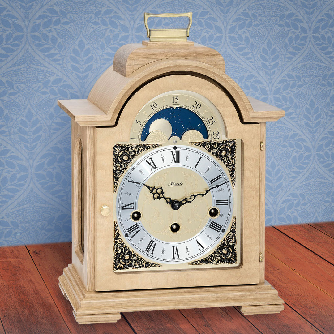 Light oak clock on wood shelf in front of blue wallpaper