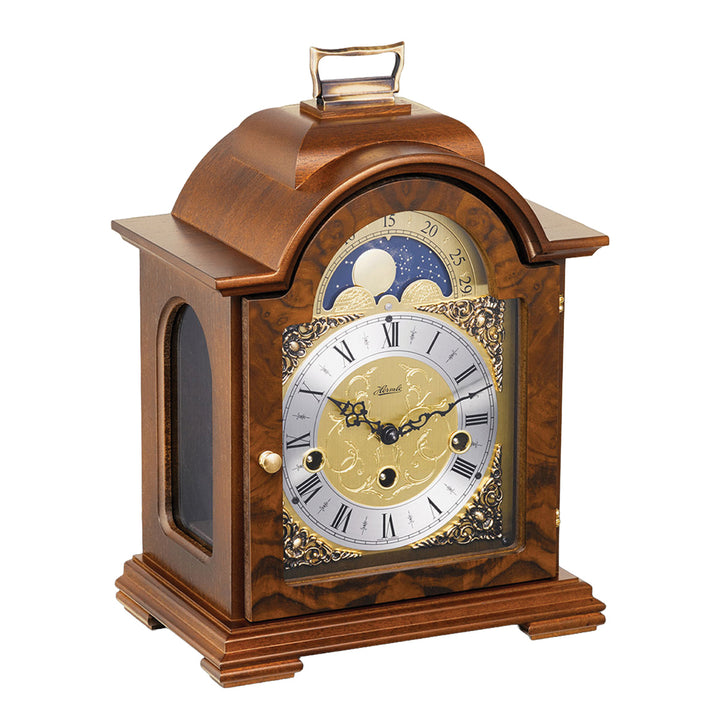 Walnut wood and brass mantel clock with roman numerals, ornate face and moon dial on white background.