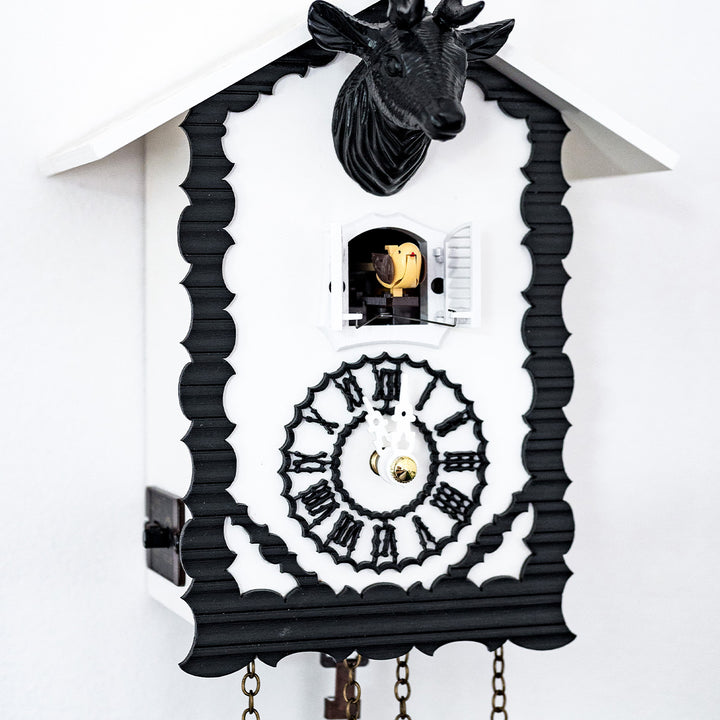 Up close of black and white cuckoo clock with cuckoo bird coming out of door and roman numeral face