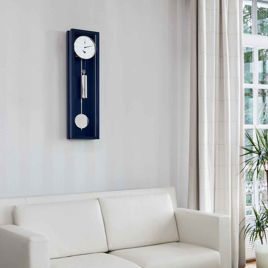Blue wall clock hung above white couch in living room 