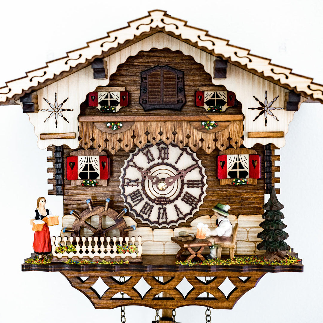Up close German cuckoo clock with roman numeral face and cottage style with figurines 