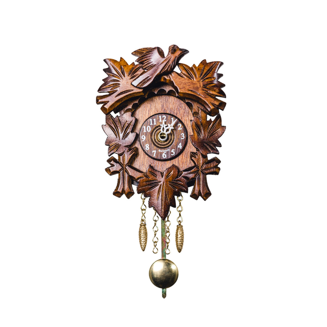 Small wooden cuckoo clock with carved leaves, brass pendulum and bird on white background.