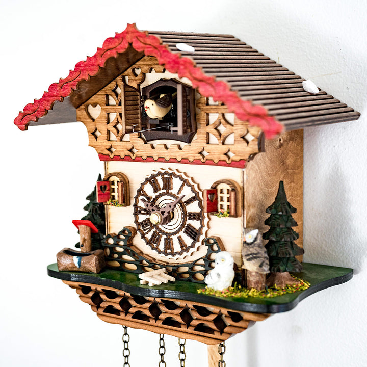 Close up of cuckoo clock with wooden roman numeral face and small owl figures