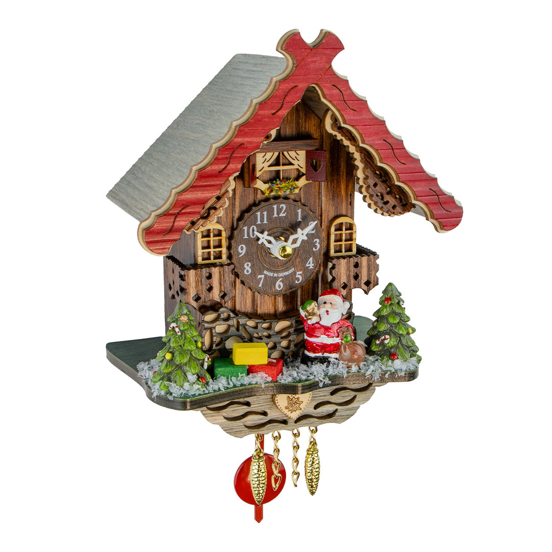 A traditional black wood cuckoo clock shaped like a mountain chalet with a red roof, featuring a clock face, miniature Christmas trees, a Santa Claus figure, and hanging ornaments.