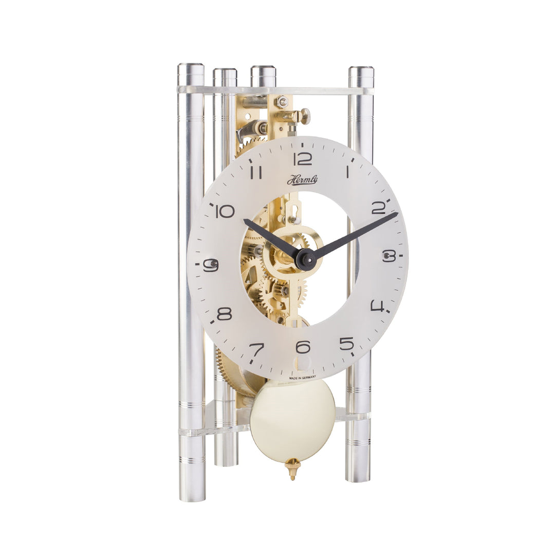 Silver and brass mechanical clock with glass face and intricate gears visible on white background