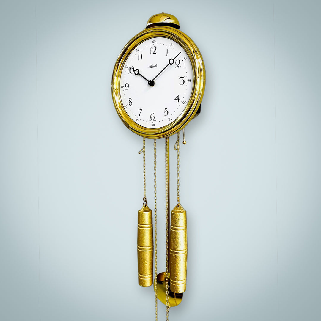 Brass clock with pendulum on gray wall