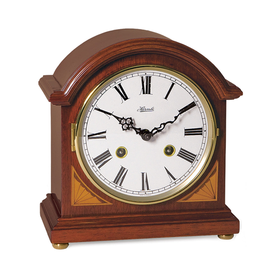Wood mantel clock with brass highlights and ornate hands on white background.