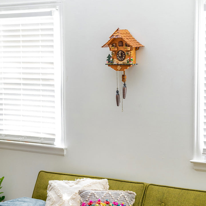Intricate wooden cuckoo clock on a white wall above a green sofa with cushions.