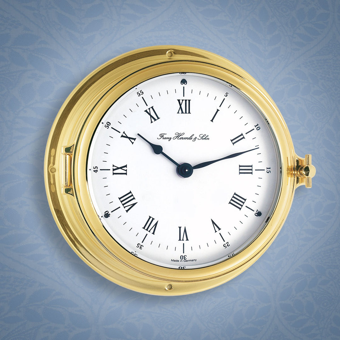 Brass ship's clock on blue vintage wallpaper