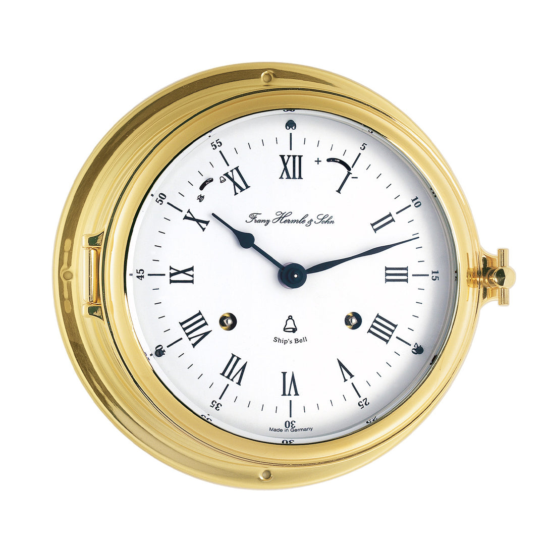 Brass ship's clock with roman numeral face on white background.