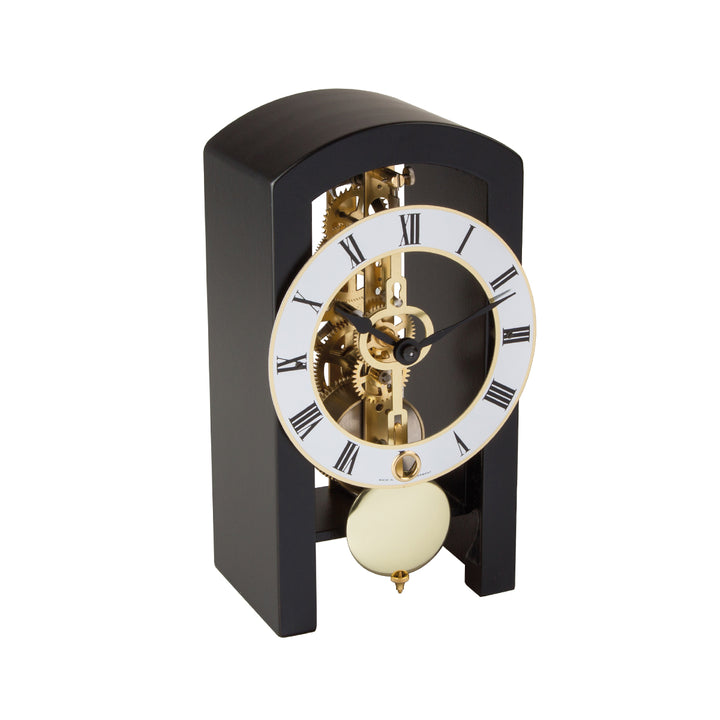 Mechanical clock with black casing and silver face highlighted by brass on a white background