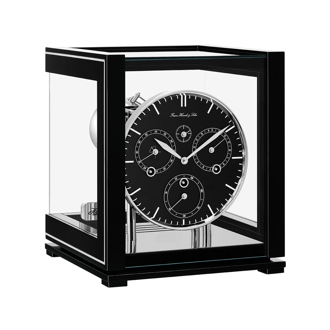 Black perpetual calendar clock with black face, silver hands and glass panels on white background.