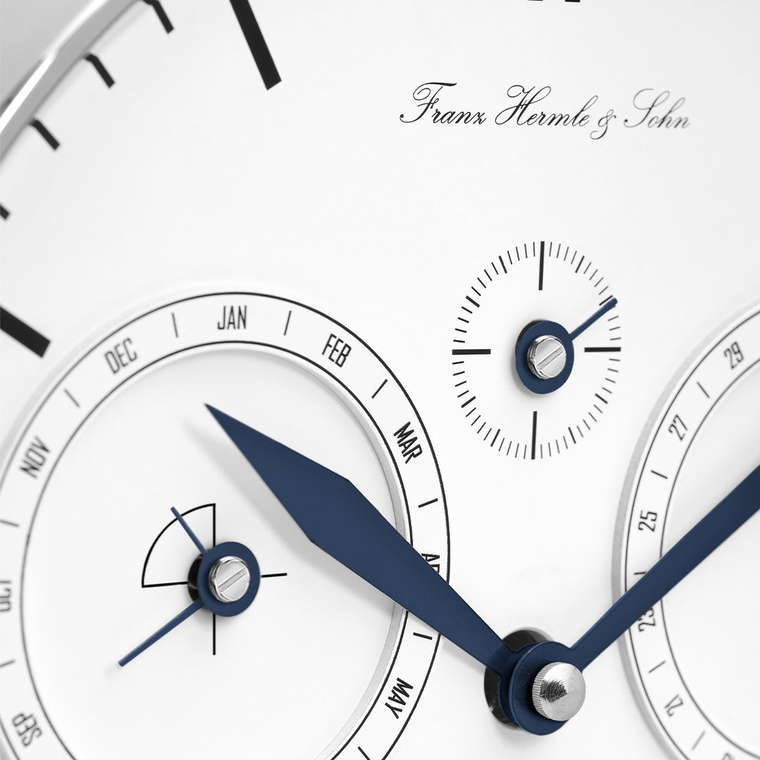 Close up of detailed clock face with blue hands, calendar dial and seconds dial.