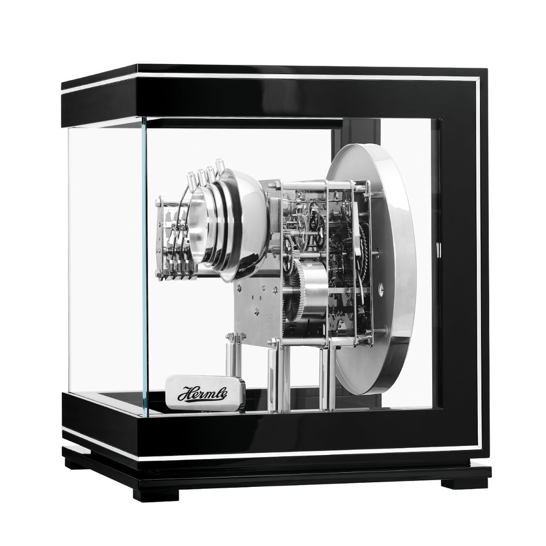 Intricate gears inside black and silver perpetual calendar clock.