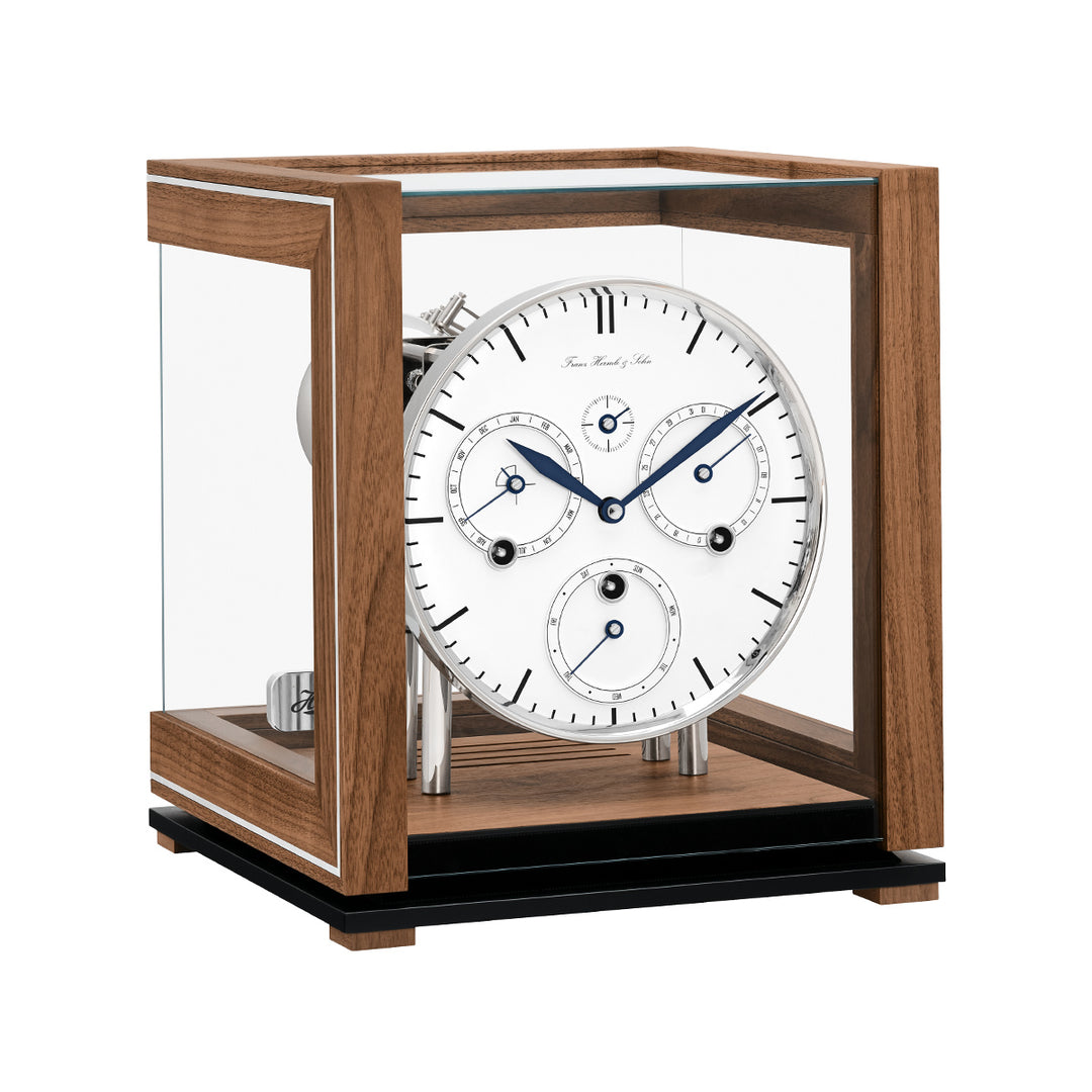 Walnut perpetual calendar clock with white face, blue hands and glass panels on white background.