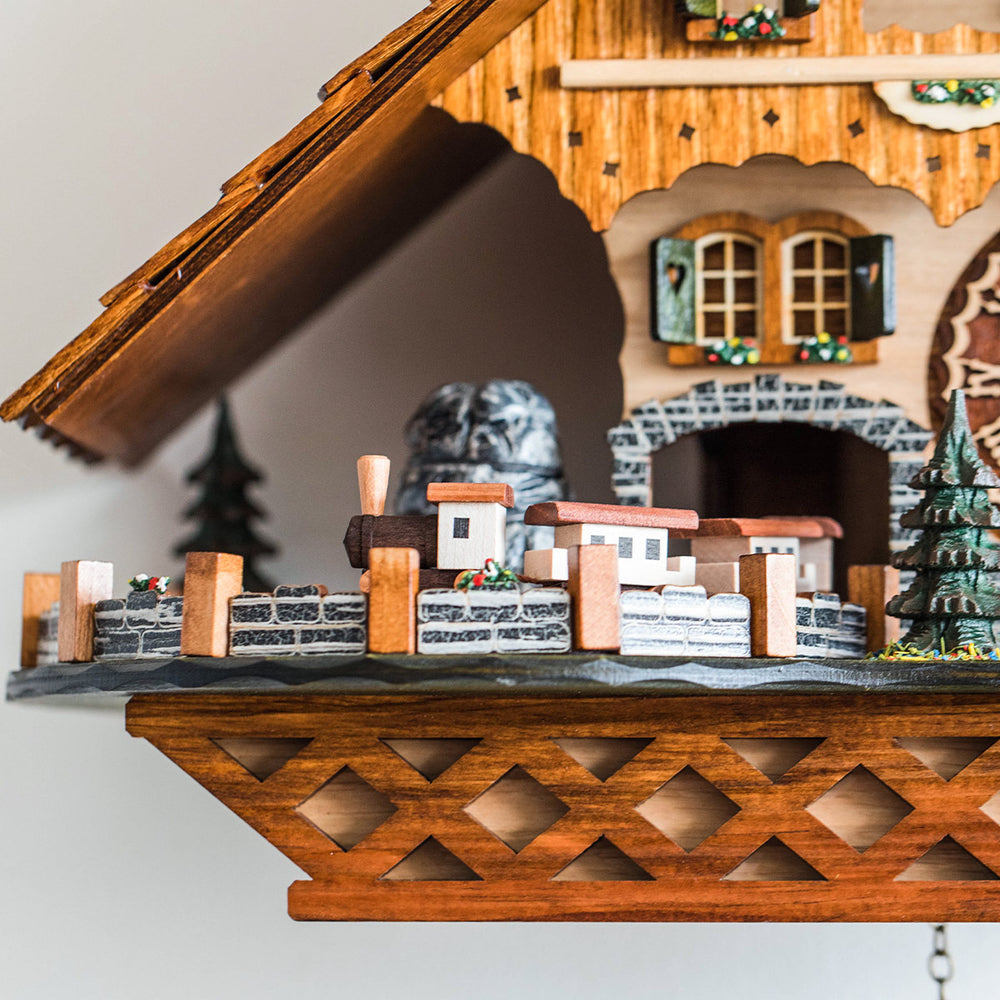 Up close view of small wooden train on detailed wooden cuckoo clock