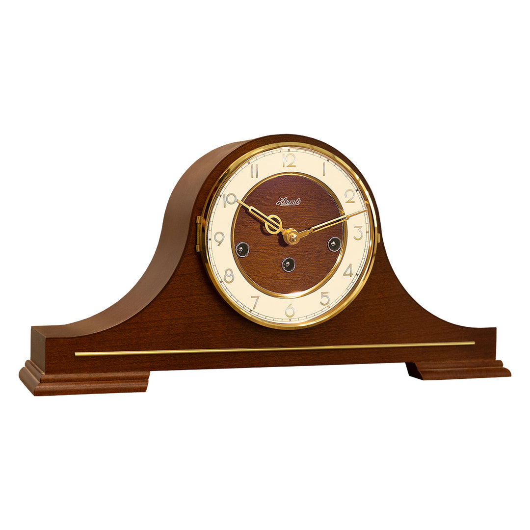 Wood and brass classic style mantel clock with Hermle logo and three winding holes on white background.