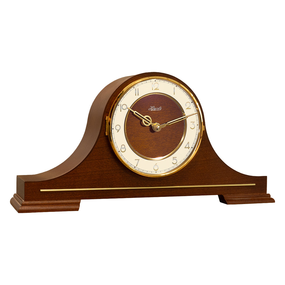Wood and brass classic style mantel clock with Hermle logo and brass arabic numerals on white background.