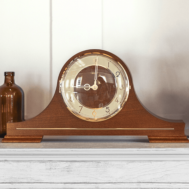 Tambour style mantel clock with an off-white face on white mantel. Clock is Stepney by Hermle in a mid-century modern style.