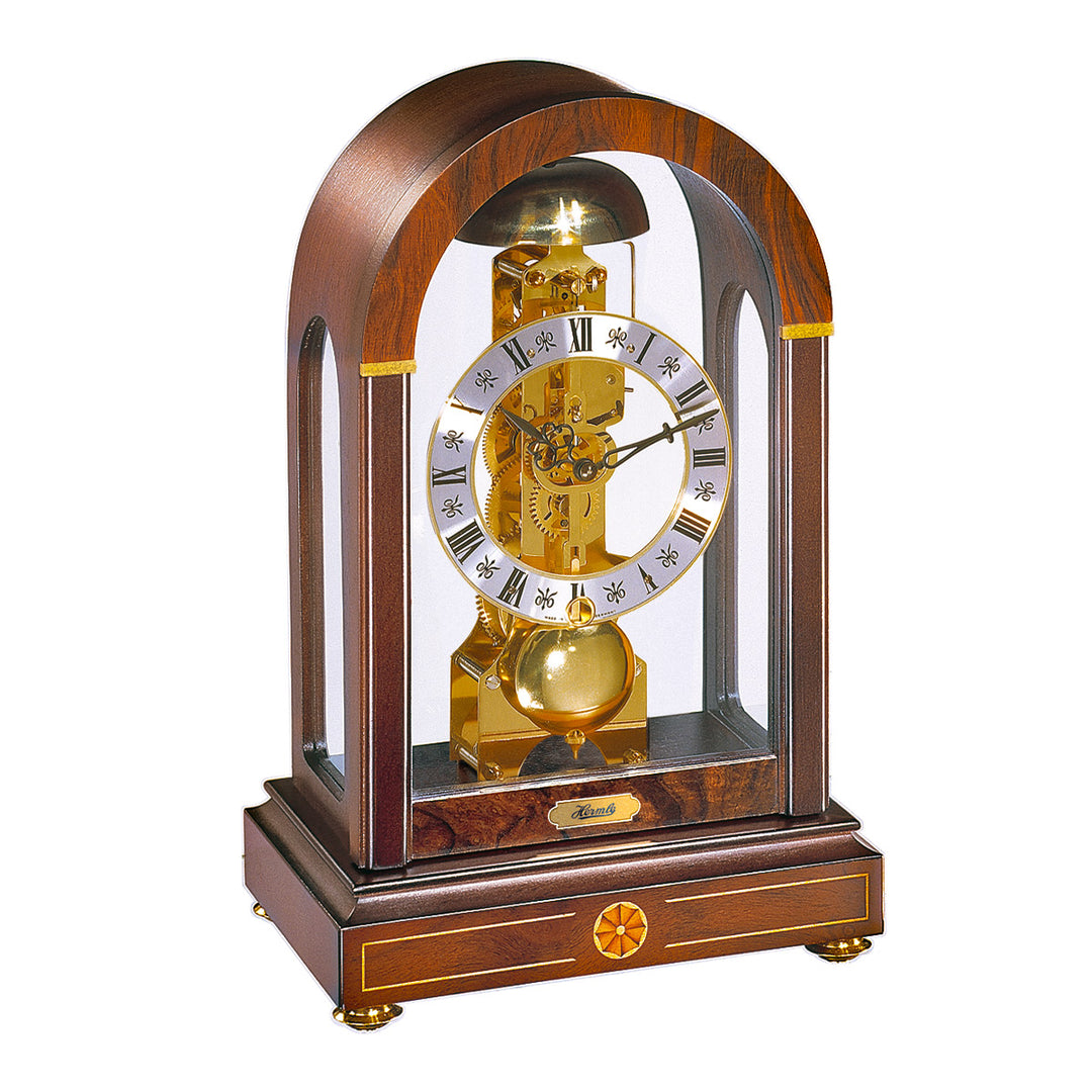 Wood mantel clock with arched glass panes and roman numeral face on white background.