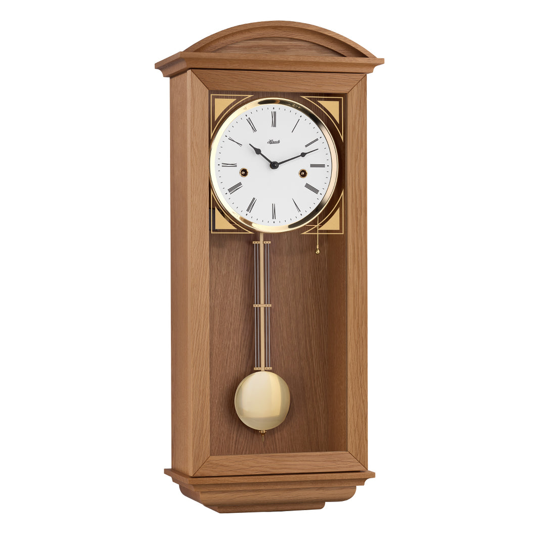 Retro style natural oak wall clock with brass highlights and two holes in the face for winding the mechanical movement inside.